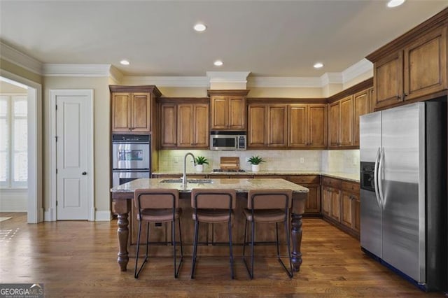 kitchen featuring sink, a kitchen island with sink, stainless steel appliances, dark hardwood / wood-style flooring, and decorative backsplash