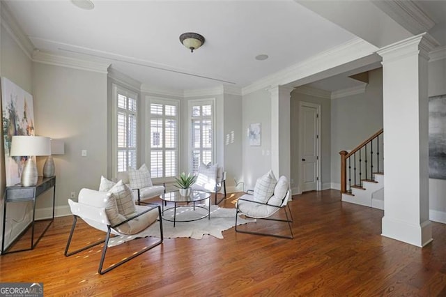 living area featuring dark wood-type flooring, ornamental molding, and decorative columns