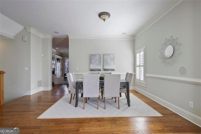 dining room with ornamental molding and dark hardwood / wood-style flooring