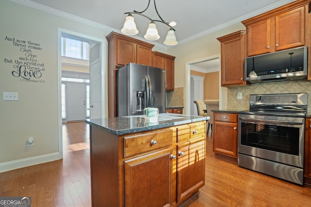 kitchen with a center island, crown molding, decorative backsplash, appliances with stainless steel finishes, and hardwood / wood-style flooring