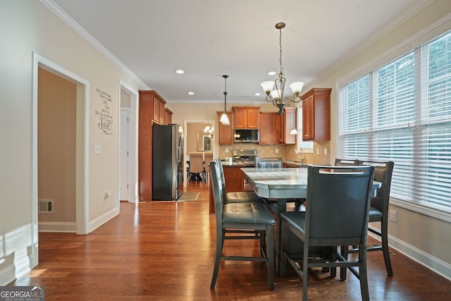 dining space featuring plenty of natural light, ornamental molding, and a chandelier