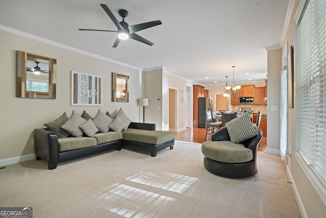 carpeted living room featuring ceiling fan with notable chandelier, a healthy amount of sunlight, and ornamental molding