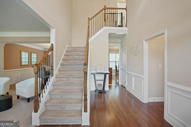 stairs with hardwood / wood-style floors and ornamental molding