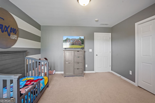 bedroom featuring light carpet and a nursery area