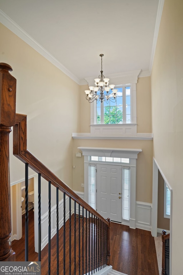 entrance foyer with dark hardwood / wood-style floors, an inviting chandelier, and ornamental molding