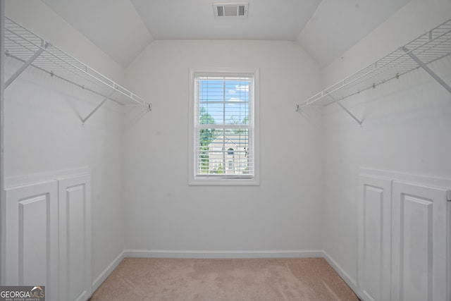 spacious closet with lofted ceiling and light carpet