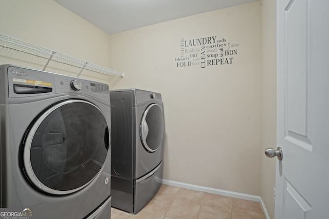 clothes washing area featuring washer and clothes dryer and light tile patterned flooring