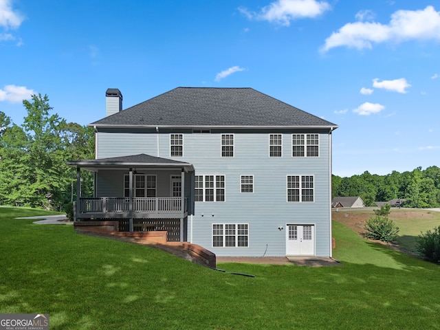 rear view of house with a wooden deck, ceiling fan, and a yard