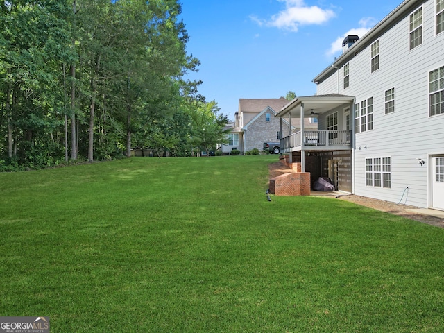 view of yard featuring ceiling fan and a deck