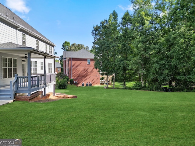 view of yard with ceiling fan and a wooden deck