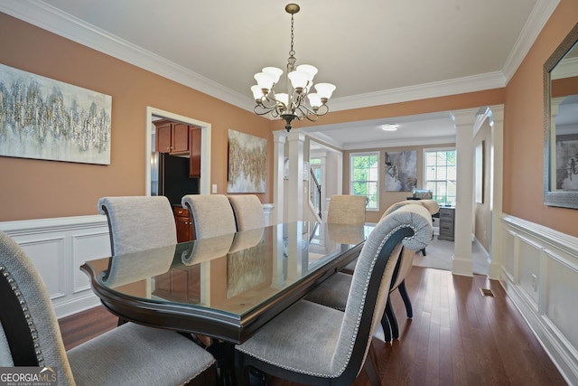 dining area with dark hardwood / wood-style floors, ornate columns, crown molding, and a notable chandelier