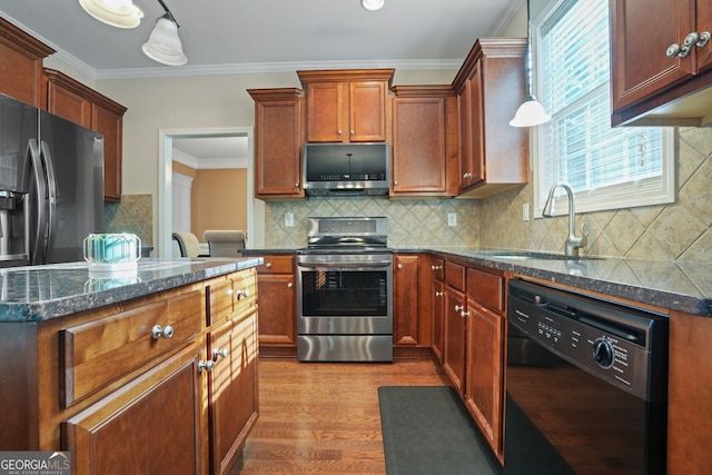 kitchen with ornamental molding, stainless steel appliances, sink, pendant lighting, and light hardwood / wood-style flooring