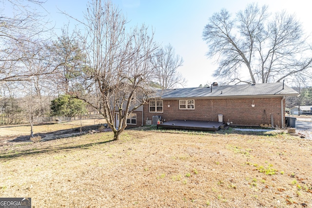 rear view of house featuring a lawn and a wooden deck