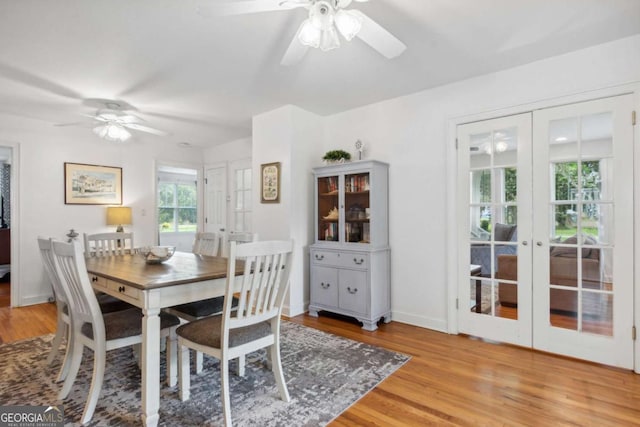 dining space with french doors, a ceiling fan, light wood-type flooring, and baseboards