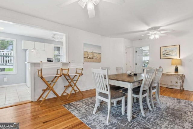 dining space featuring a ceiling fan, baseboards, and light wood-type flooring