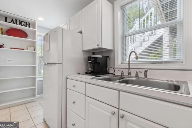 kitchen featuring a sink, plenty of natural light, white cabinets, and light tile patterned floors