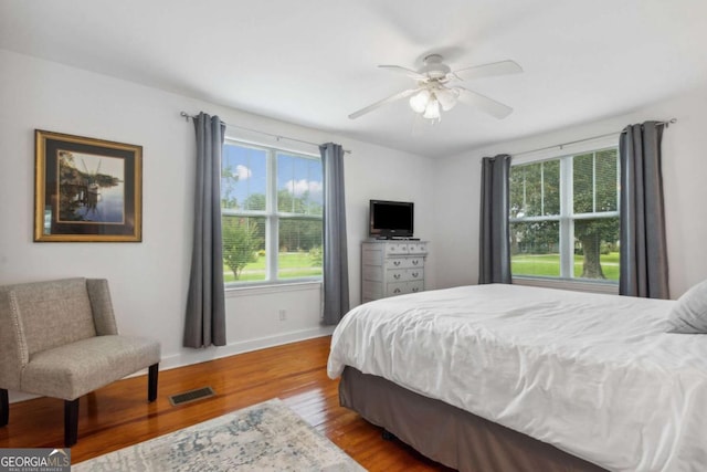 bedroom featuring visible vents, a ceiling fan, baseboards, and wood finished floors