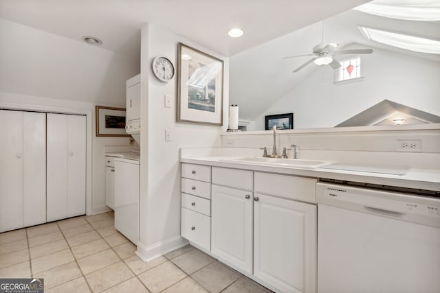 bathroom with lofted ceiling with skylight, stacked washing maching and dryer, tile patterned floors, vanity, and a ceiling fan