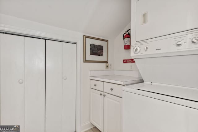 clothes washing area with cabinet space and stacked washer and clothes dryer