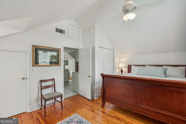 bedroom with a closet, visible vents, light wood-style floors, and vaulted ceiling