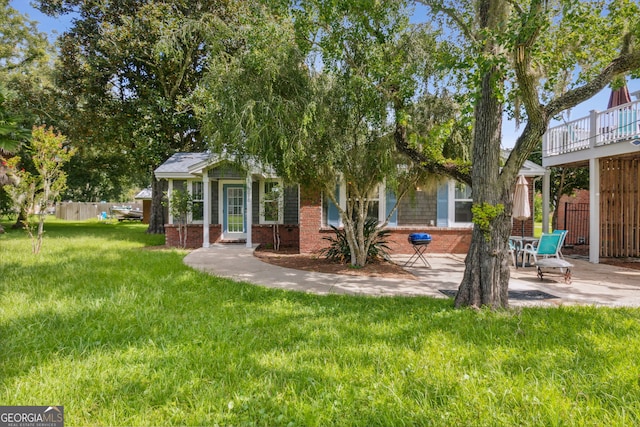 back of property featuring brick siding, a lawn, a patio, and fence