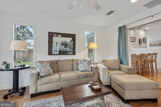 living room featuring ceiling fan, wood finished floors, visible vents, and baseboards