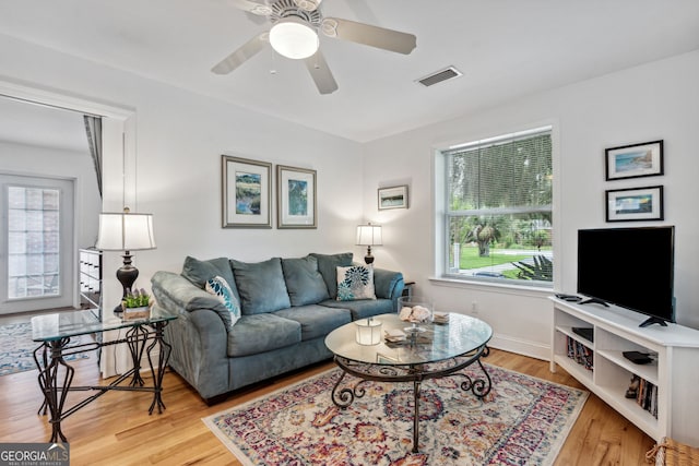 living room featuring visible vents, baseboards, wood finished floors, and a ceiling fan