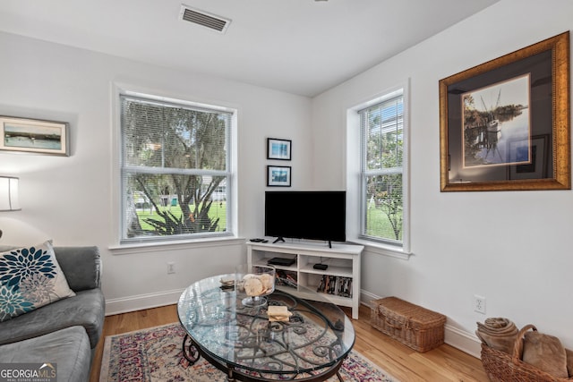 living area featuring visible vents, baseboards, and wood finished floors