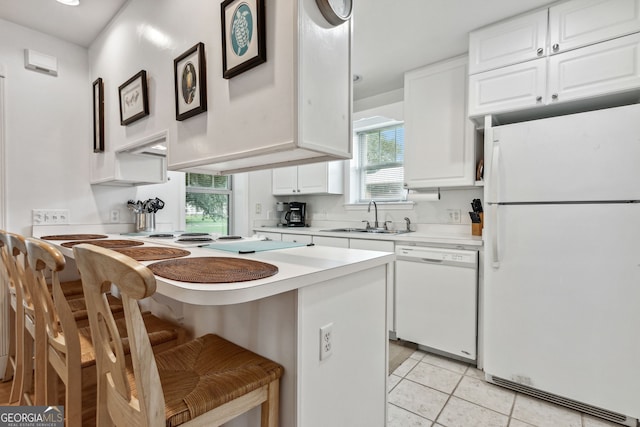 kitchen featuring a breakfast bar, a sink, white cabinetry, white appliances, and light countertops