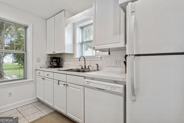 kitchen with white cabinetry, white appliances, light tile patterned flooring, and a sink