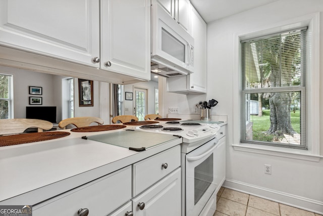 kitchen with baseboards, light countertops, light tile patterned flooring, white appliances, and white cabinetry