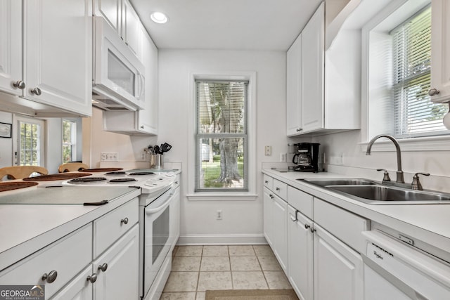 kitchen featuring a sink, white appliances, white cabinets, light countertops, and baseboards