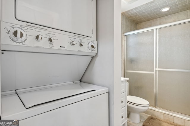 bathroom with toilet, a stall shower, and stacked washing maching and dryer