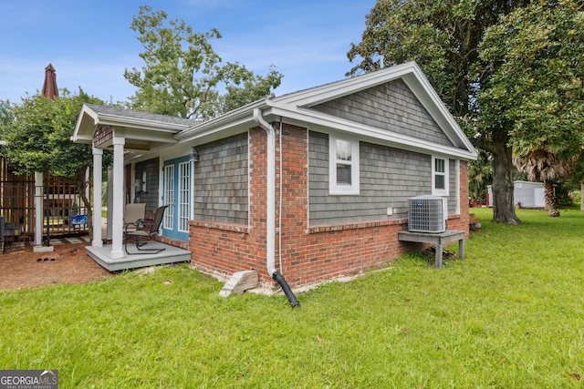 view of property exterior with fence, cooling unit, a lawn, and brick siding