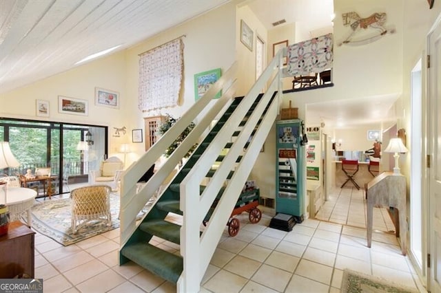 staircase featuring tile patterned flooring and high vaulted ceiling