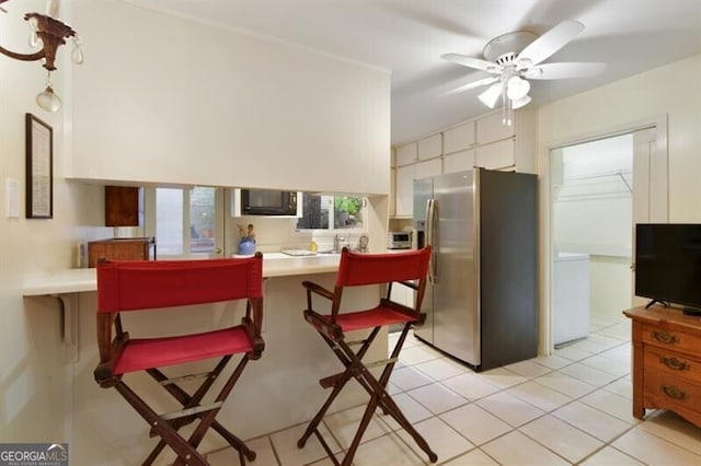 kitchen featuring a breakfast bar, stainless steel refrigerator with ice dispenser, ceiling fan, light tile patterned flooring, and kitchen peninsula