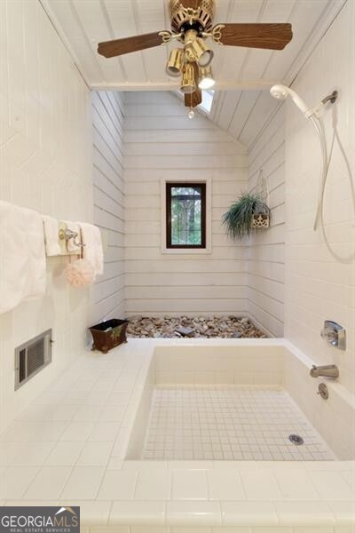 bathroom with ceiling fan, lofted ceiling, and tiled shower