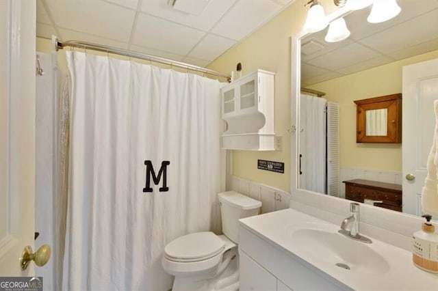 bathroom with curtained shower, a drop ceiling, vanity, and toilet