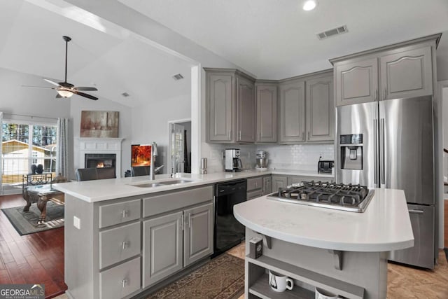kitchen with appliances with stainless steel finishes, a center island, gray cabinets, and backsplash
