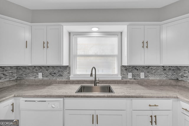 kitchen featuring tasteful backsplash, white cabinets, sink, and white dishwasher