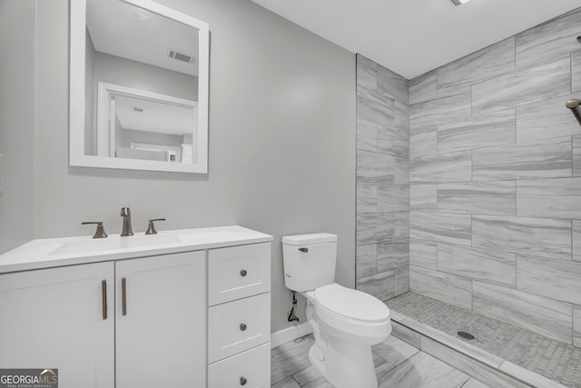 bathroom featuring tiled shower, vanity, and toilet