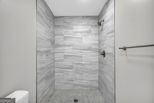 bathroom featuring toilet and a tile shower