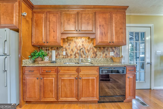 kitchen with light stone counters, sink, light hardwood / wood-style flooring, dishwasher, and white fridge