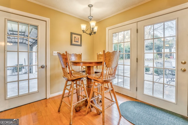 dining room featuring a textured ceiling, light hardwood / wood-style floors, crown molding, and a notable chandelier