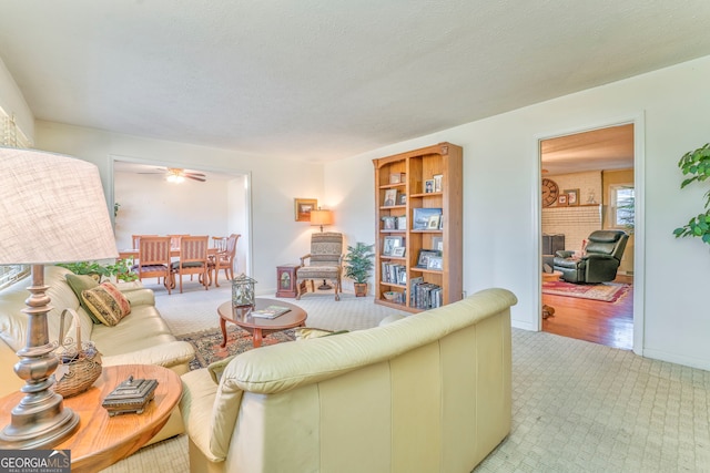 living room featuring light carpet, a textured ceiling, and ceiling fan