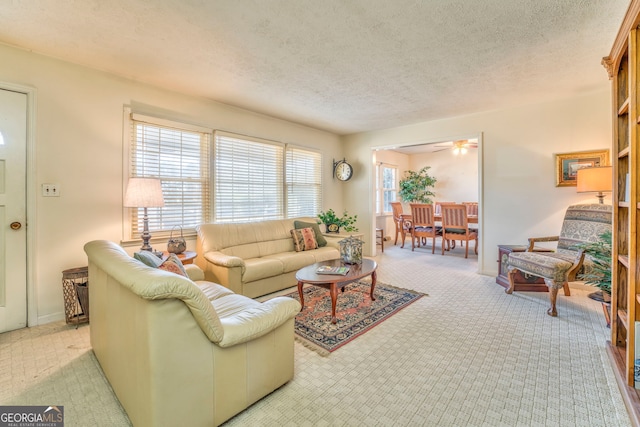 carpeted living room featuring ceiling fan and a textured ceiling