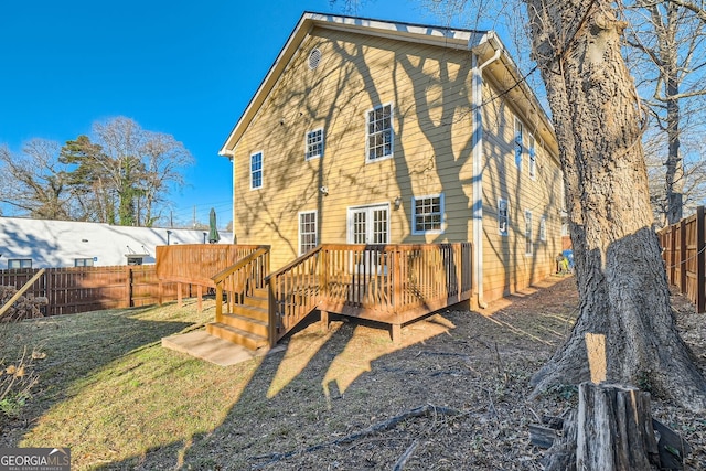 back of property with a deck and a lawn