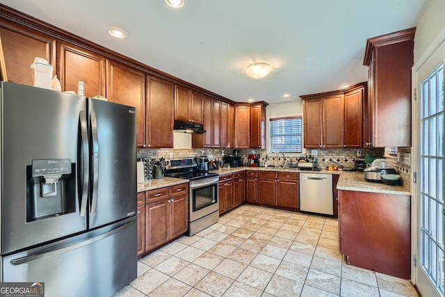 kitchen featuring tasteful backsplash, light stone counters, light tile patterned floors, and appliances with stainless steel finishes