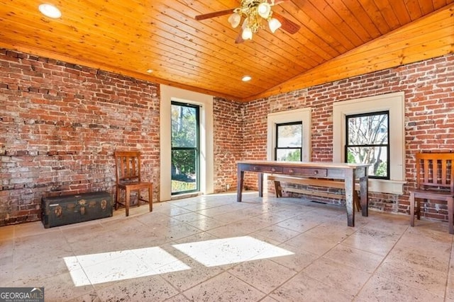 unfurnished office with ceiling fan, lofted ceiling, and brick wall