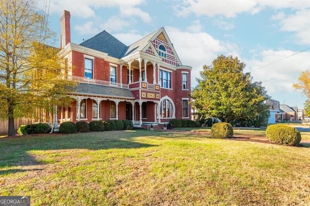 victorian house featuring a front yard and a balcony